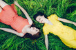 Two sisters lie in the grass and look at each other