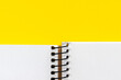 © MariiaDemchenko - Open spiral notebook with blank empty white sheets in the bottom of a bright yellow background, closeup top view with copy space