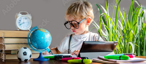 Back to school. Distance Learning at home during quarantine, lockdown in the pandemic of coronavirus covid.19 Todler boy with glasses studying remotely, digital learning.School