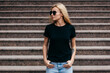 © andrew_shots - Stylish blonde girl wearing black t-shirt and glasses posing against street , urban clothing style. Street photography