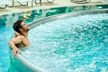 Happy man with eyes closed relaxing in hot tub at the spa.