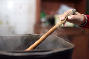 hands cooking with a wooden spoon