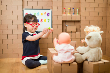 Wall Mural - toddler girl pretend play as a teacher at home