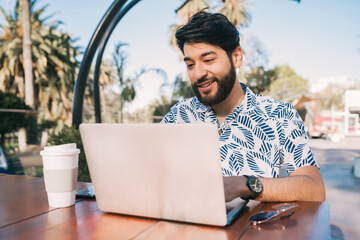 Wall Mural - Young man using his laptop in a coffee shop.