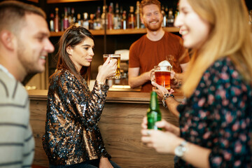 Wall Mural - Group of friends hanging on in a pub, chatting and drinking beer.