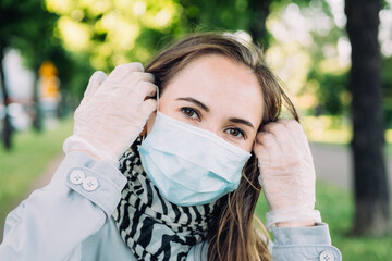 A young Caucasian girl went for a walk in the park wearing medical gloves and a mask