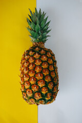 ripe juicy tropical pineapple on a yellow-white background. Space for text. Pineapple on a wooden table