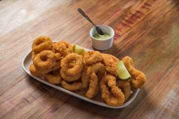 Breaded squid (Milanesa), served in a dish on a rustic wooden table