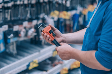 Wall Mural - The buyer in the hardware store selects the goods. A man holds a wrench in his hand.