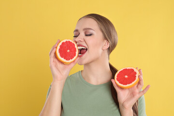 Sticker - Emotional young woman with cut grapefruit on yellow background. Vitamin rich food