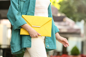 Young woman with elegant envelope bag outdoors on summer day, closeup