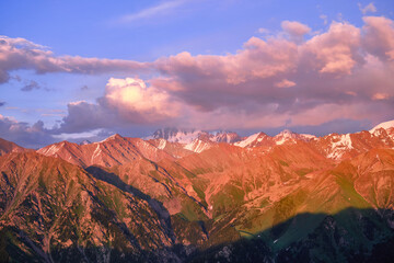 Wall Mural - Grandiose mountain valley with ridges of snowy peaks at sunset