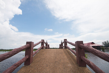 The cemented bridge connects the path to the lake in the middle of the water on a clear day. In beautiful nature