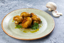 Close-up Of Delicious Lightly Fried Champignons In A Plate On A Gray Background