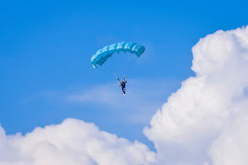 Skydiver and colorful parachute on the blue sky 