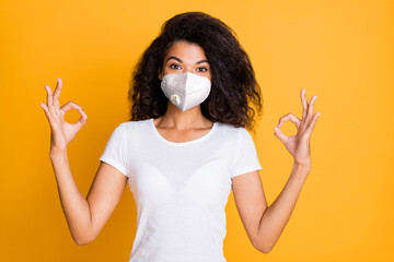 Wall Mural - Close-up portrait of her she nice attractive healthy wavy-haired girl wearing safety respirator mask showing ok-sign mers cov pathogen syndrome isolated vivid yellow color background