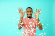 © Carlos David - Portrait of a cheerful black man smiling looking at camera with his hands up and trowing confetti