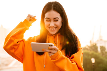 Wall Mural - Photo of asian woman making winner gesture while playing video game