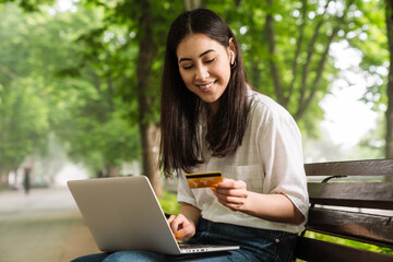 Poster - Photo of happy asian woman using laptop and holding credit card