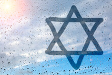 Figure Eight-pointed Star, A Symbol Of Judaism, On Wet Glass. Glass Window With Raindrops Against The Sky. The Concept Of The Jewish Religion.
