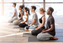Wellness Concept. Young Sporty People In Yoga Class Making Meditation Exercises Together