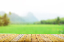 Shelf Of Brown Wood Plank Board With Blurred Green Rice Field Farm With Mountain And Hut Nature Background.