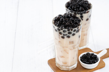 Bubble milk tea with tapioca pearl topping, famous Taiwanese drink on white wooden table background in drinking glass, close up, copy space