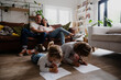 © Prins Productions - Caucasian family in the living room together, spending quality family time. Kids drawing on the floor while mother and father laugh together