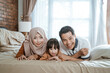 © Odua Images - Asian Muslim families laugh happily looking at the camera while lying together on the bed