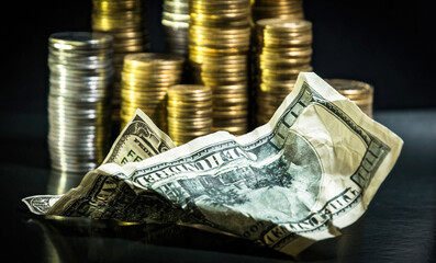 Wall Mural - Piles of coins of various denominations on a black background and a crumpled hundred dollar bill . Investments and Savings	