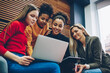 © BullRun - Group of multiracial female students watching training webinar together on laptop computer in campus ,young women best friends browsing web store page for making shopping during free time on netbook