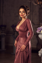 Young Beautiful Lady In Evening Dress Posing In Dark Interior And Looking At You