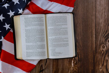 Open Is Reading Holy Bible Book With Prayer For America Over Ruffle American Flag In Wooden Table