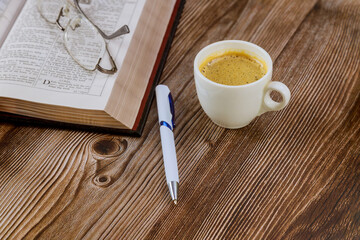 Wall Mural - Personal study with Holy Bible with black coffee cup on pen with eyeglasses over wooden background