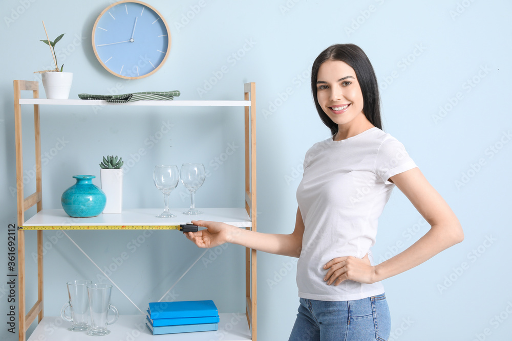 Young woman taking measures of rack in room