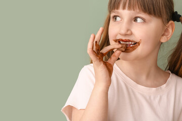 Wall Mural - Cute funny girl with chocolate on her face and hands against color background