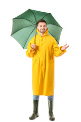 Wall Mural - Young man in raincoat and with umbrella on white background