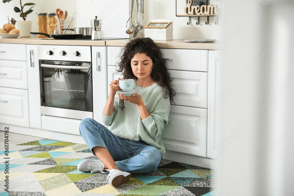 Beautiful young woman drinking hot tea at home