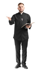 Wall Mural - Handsome young priest with Bible on white background