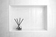 black and white photo of luxury glass aroma scent reed diffuser bottles with yellow oil are displayed in the nice white toilet bahtroom to creat relax and cleaness ambient