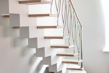 Elegance contemporary designed stairs in a white modern room of luxury apartment. No people, natural lighting.