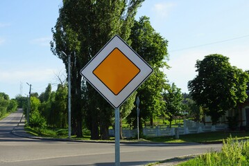 one road sign the main road on a metal pillar against a blue sky and green vegetation