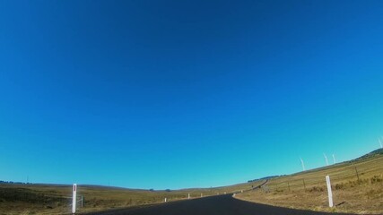Wall Mural - driver’s view of the capital wind farm showing large wind turbines located along a countryside road 