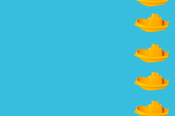 Several yellow plastic children s boats on a light blue background with copy space