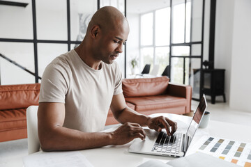 Wall Mural - Photo of african american man working with laptop while sitting at table