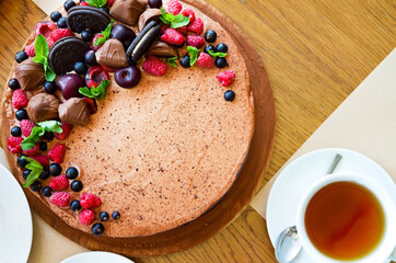 Chocolate cake in cocoa from above berries raspberries, black currant, biscuits, sweets on a round plate on the table. Cake slice, berries in macro. Birthday cake number 2. Top view, side view. 