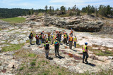 Fototapeta Sawanna - SUDBURY, ONTARIO, CANADA - MAY 21 2009: Group of workers and geologists in hardhats and high-visibility vests standing on geological outcrop site.