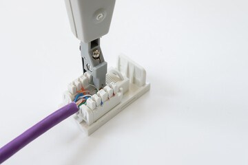 Close-up view of a networking cabling tool used to punchdown data cable wire to the back of a data outlet socket.