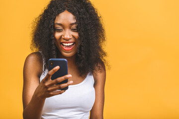 Portrait of her she nice attractive lovely winsome focused cheerful cheery wavy-haired african american black girl holding in hands phone chatting on web isolated over yellow background.