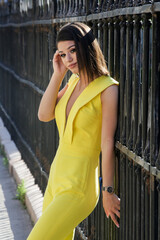 Wall Mural - Outdoor portrait of young fashionable woman wearing a yellow jumpsuit